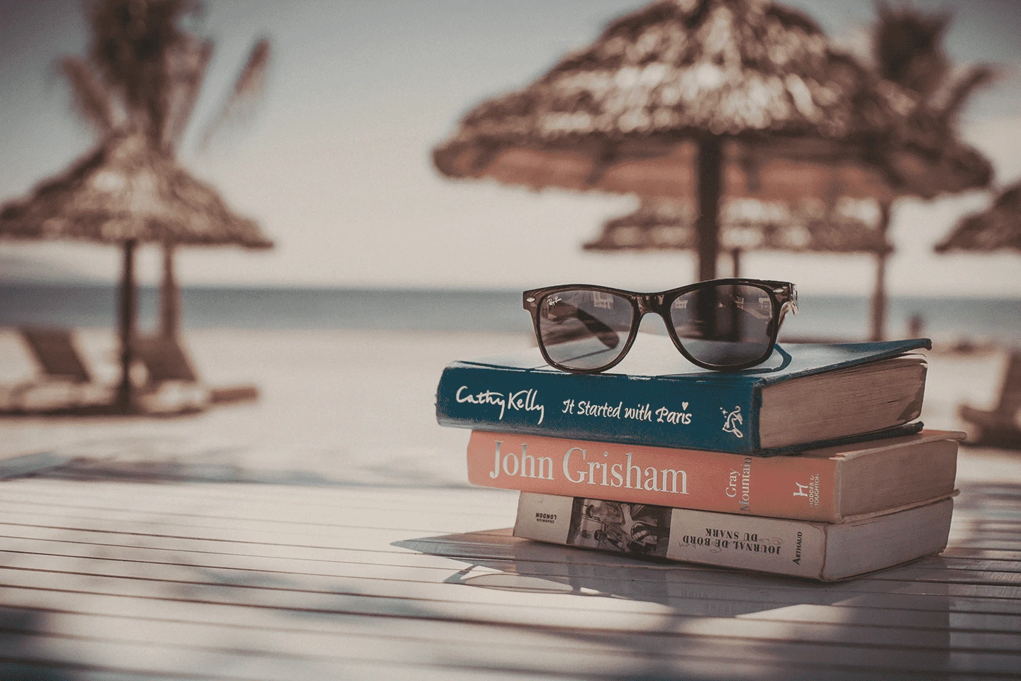 Foto de vacaciones en la playa, con gafas de sol y libros.